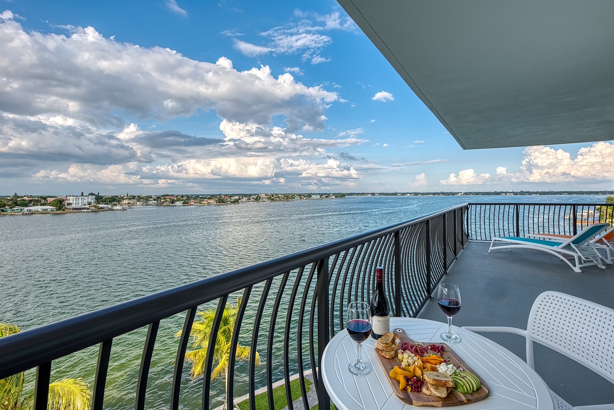 a table with food and wine on a balcony overlooking water